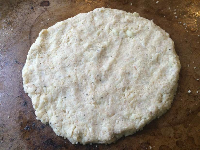 On a warmed pizza stone shape the riced cauliflower into a pizza